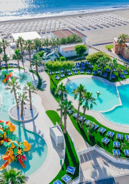Resort con piscine, scivoli e spiaggia privata con ombrelloni.