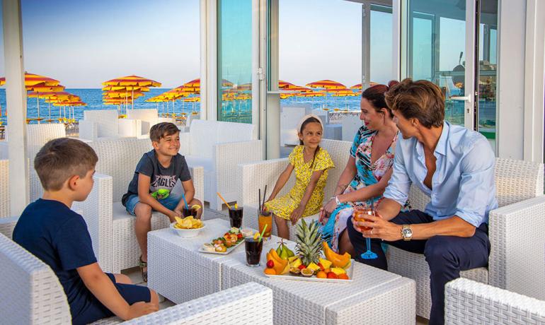Happy family at beach bar with fruit and drinks.