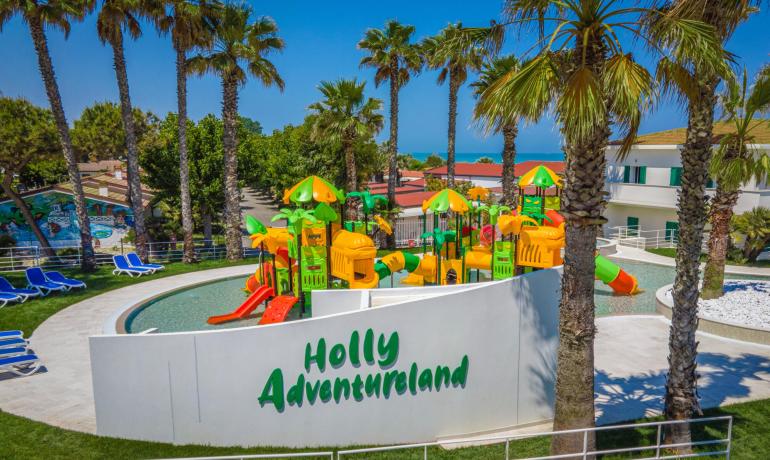 Colorful water park with slides, palm trees, and sea view.