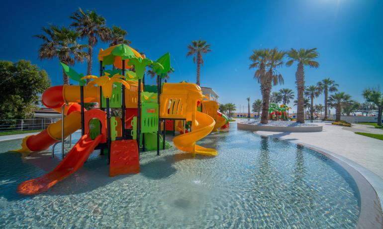 Colorful water park with slides and palm trees under a clear sky.
