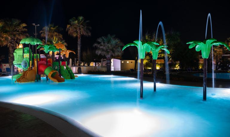 Night-lit pool with water playground for children.