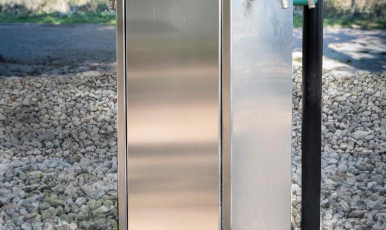 Outdoor water dispenser with taps on gravel.