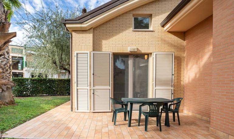 Maison avec patio, table et chaises dans le jardin.