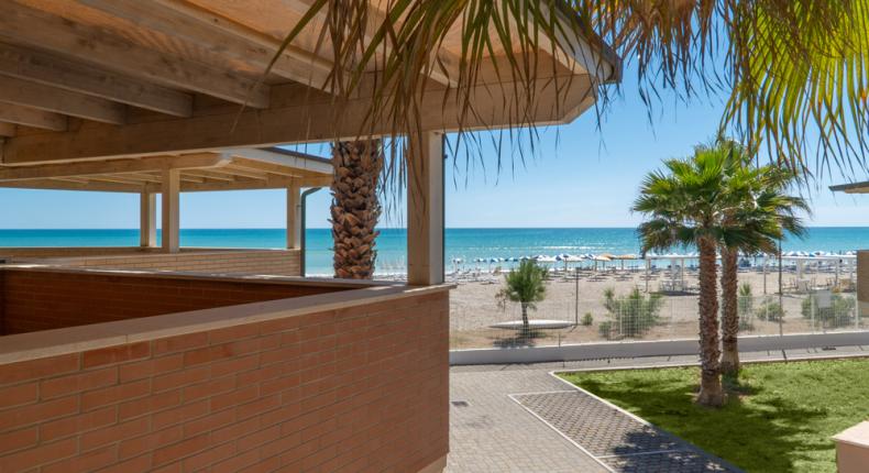 Vista sulla spiaggia con palme e mare blu.