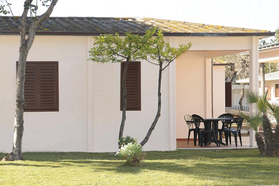 Giardino sereno con veranda e sedie, atmosfera rilassante e accogliente.