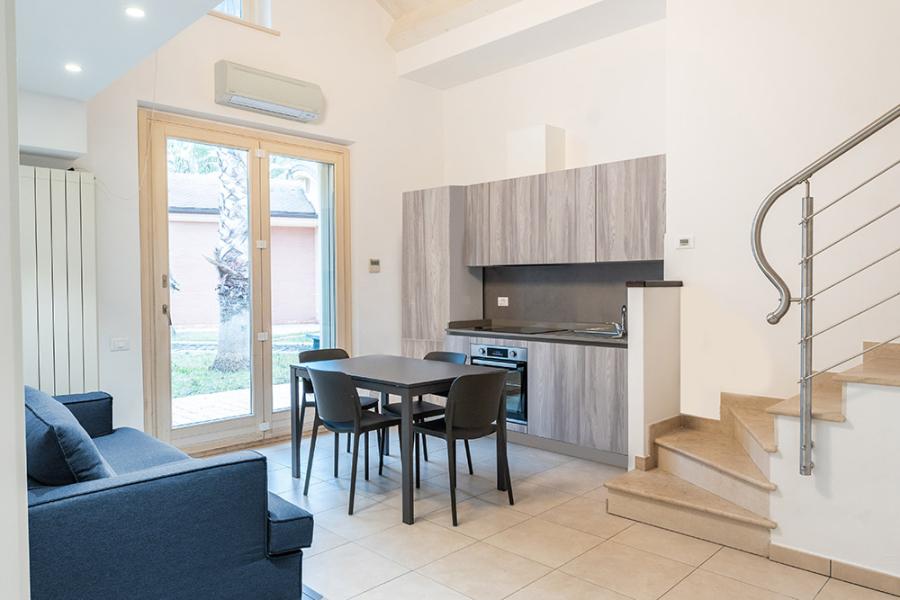 Moderno soggiorno con cucina, divano e scala.